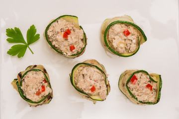 Grilled zucchini rolls with curd cheese and tuna on plate.