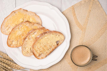 Fresh bread, homemade butter and coffee on wooden background.
