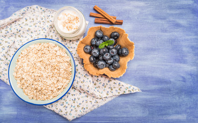 Waffle with blueberries and mint leaf. Yogurt with cinnamon and bowl of oatmeal.
