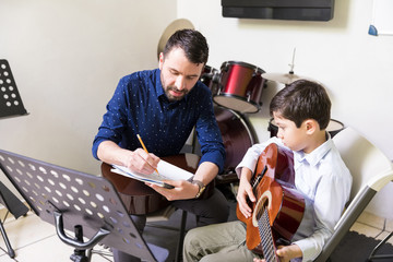 Boy Learning Music Sheet And Guitar In Class