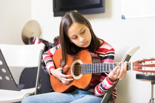 Little girl playing the guitar in music school