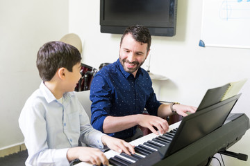 Boy Learning To Play Piano From Smiling Instructor