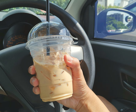 Close up image of hand holding a mug of ice cappuccino inside the car. Selctive focus, shallow dof. 