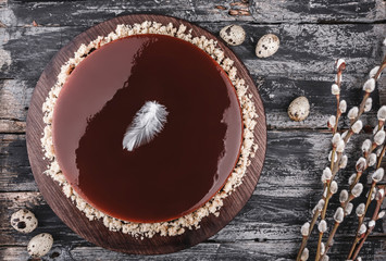 Easter cake with mirror glaze chocolate on rustic background with spring flowers, quail eggs. Happy Easter celebration. Top view, flat lay