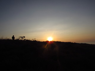 silhouette of man on top of mountain at sunset