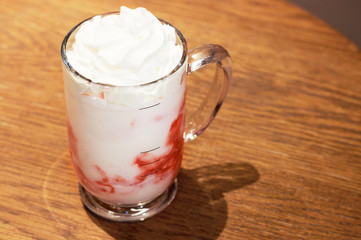 milkshake with cream in a glass on a wooden table