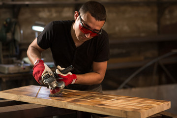 Worker creating scratches on wooden board by using polishing machine with iron wire.