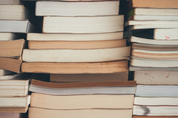 Stack of many old books background on shelf in book store or library room, vintage tone. Knowledge learning, education, bachelor degree in university or back to school concept.