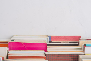 Stack of many old books on table in book store or library room with white wall background and copy space. Knowledge learning, education, bachelor degree in university or back to school concept.