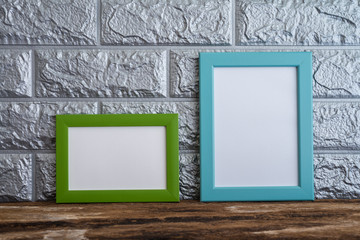 Green and blue photo frame on old wooden table over brick wallpaper background