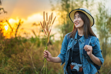 female tourist with backpack and camera in countryside with sunset