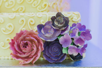 White three tier wedding cake with purple flowers decor