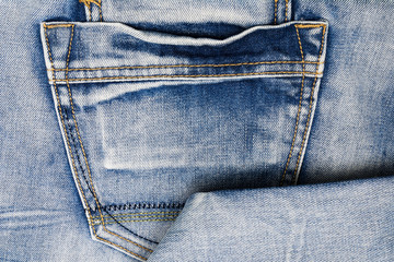 The texture of the worn blue jeans with a pocket.Denim background