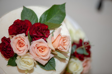 White three tier naked wedding cake with pink, red and white roses