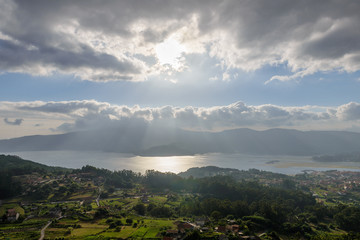 sun behind the clouds over the ocean bay