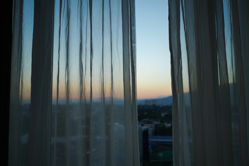 Fototapeta na wymiar sunlight through white curtain with sunset sky view outside the window