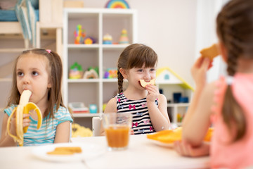 Obraz na płótnie Canvas Funny children eating healthy food. Kids lunch at daycare or kindergarten.