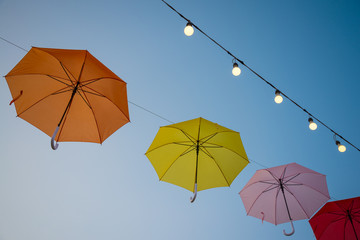 Colorful umbrella and round bulb lighting decoration in evening outdoor summer festival with blue...