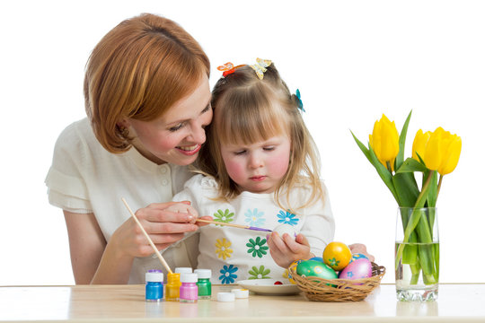 Happy mother and child daughter painting on Easter eggs