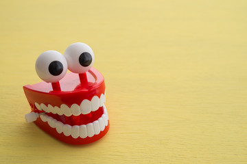 Chattering teeth toy wind up moving on yellow background. Funny, comedy, relax time concept