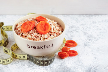 Cereal flakes, dried apricots and measuring tape on wooden background. The concept of diet, healthy Breakfast.