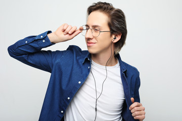 young handsome man on white studio background listening to music on earphones