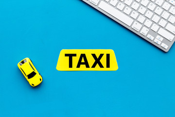 Choose, select taxi concept. Order taxi online. Sign ner car toy and keyboard on blue background top view copy space