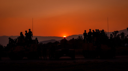 Fototapeta na wymiar twilight landscape silhouette military on the sunset background