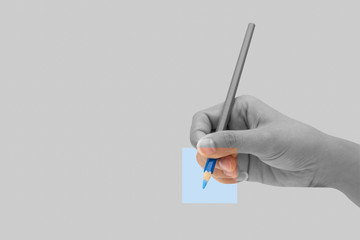 Female hand with blue color pencil isolated on grey background.