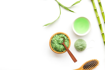 Asian spa treatment concept with natural ingredients. Spa salt, lotion, sponge near bamboo on white background top view copy space