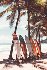 Surfboard and palm tree on beach background.