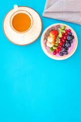 Light breakfast or healthy snack. Acai smoothie bowl with fresh fruits, berries, chia seeds on blue background top view space for text