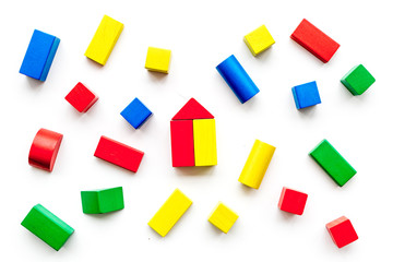 Construction game for kids. Wooden building blocks, toy bricks on white background top view