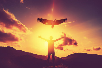 Man raise hand up on top of mountain and sunset sky with eagle bird fly abstract background.