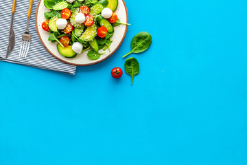 Healthy lunch. Fresh vegetable salad on blue background top view space for text