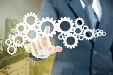 Businessman pointing his finger on gear elements
