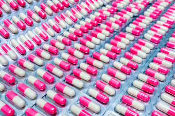 Pink-white antibiotic capsule pills in blister pack. Antibiotics drug resistance. Pharmaceutical packaging industry. Global healthcare. Pharmacy background. Pharmaceutical product. Production line.