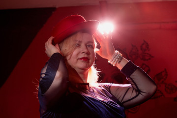 Fat woman wearing a hat in a dark room with red light. Gangsters style