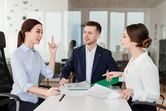 Successful young employees working together excited about new idea they have. Business concept of co-workers in the office space.