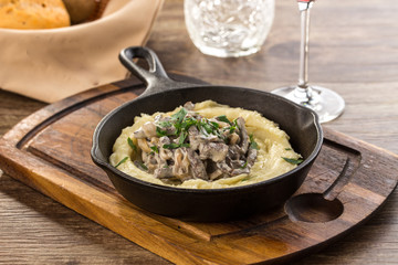 Beef stroganoff with mushrooms in frying pan on wooden table