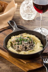 Beef stroganoff with mushrooms in frying pan on wooden table