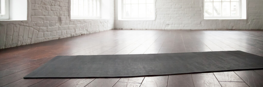Horizontal photo yoga mat on wooden floor at sport club