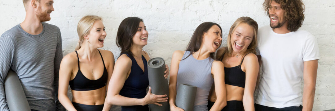 Laughing people resting after workout standing in row near wall