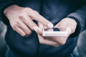 Close up man hand hold using smart phone on outdoor park street background.