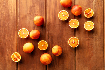 An overhead photo of organic blood oranges, whole and cut, on a dark rustic background, forming a...