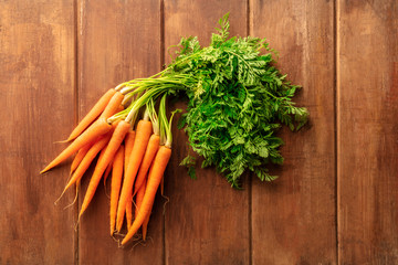 An overhead photo of fresh organic raw carrots on a dark rustic wooden background with copy space