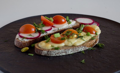 Multigrain toast bread with melt gouda or kaseri cheese and small tomatoes radish and green onion on top