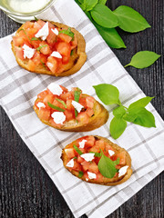 Bruschetta with tomato and feta on dark board top