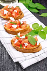 Bruschetta with tomato and feta on dark board