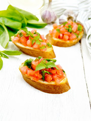 Bruschetta with tomato and spinach on white board